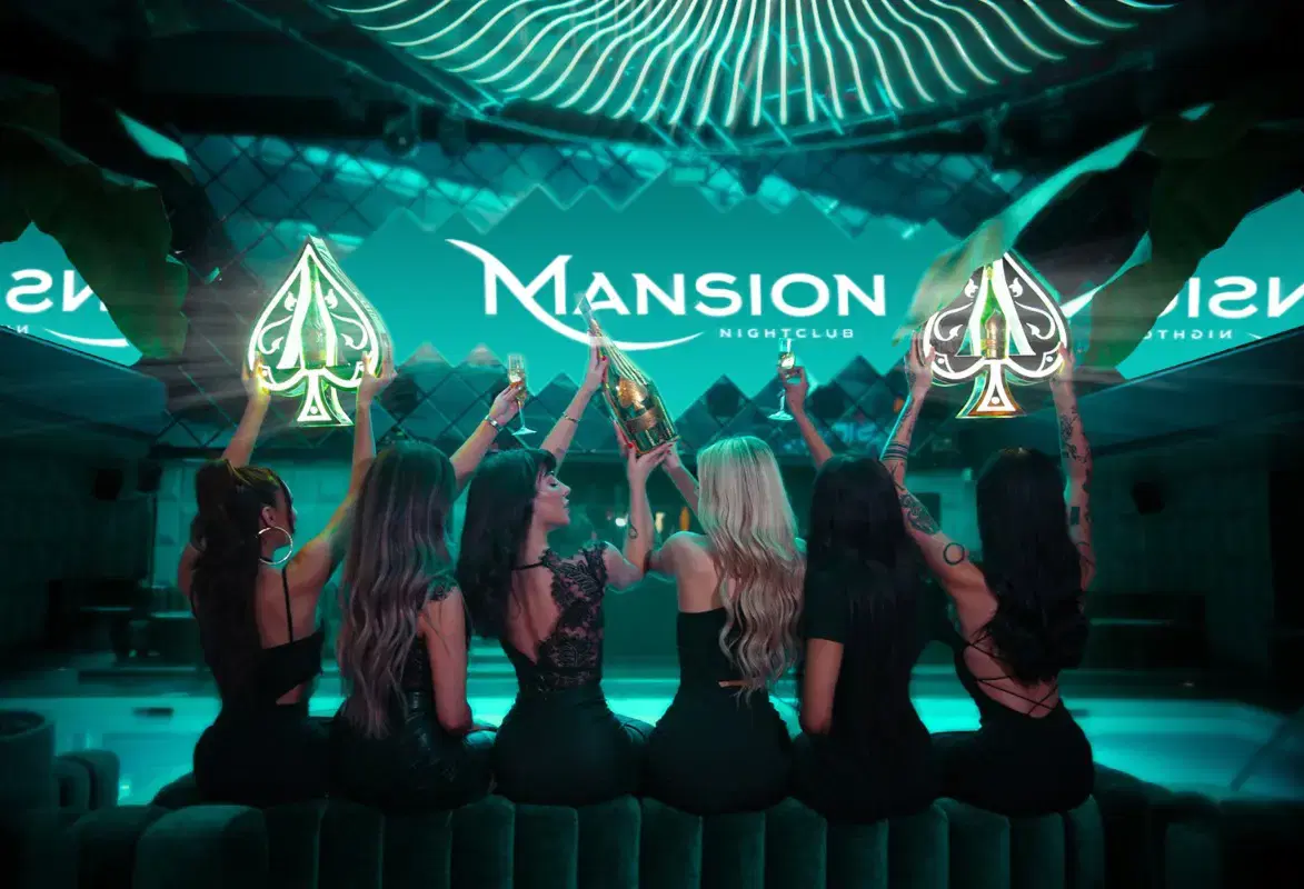 Mansion Nightclub bottle servers holding bottles, presenters, and glasses of champagne sitting down from behind
