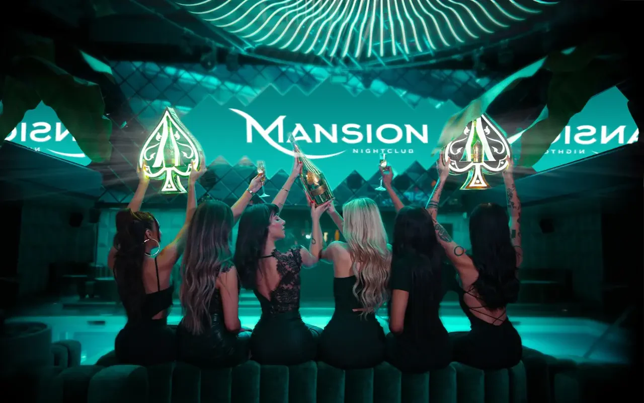 Mansion Nightclub bottle servers holding bottles, presenters, and glasses of champagne sitting down from behind